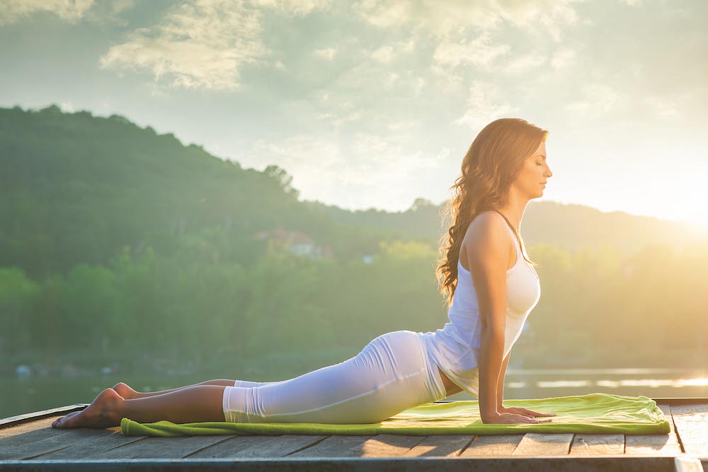 Woman doing yoga on the lake - relaxing in nature